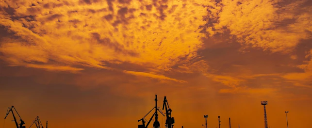 Zarys portu morskiego w świetle zachodzącego słońca.